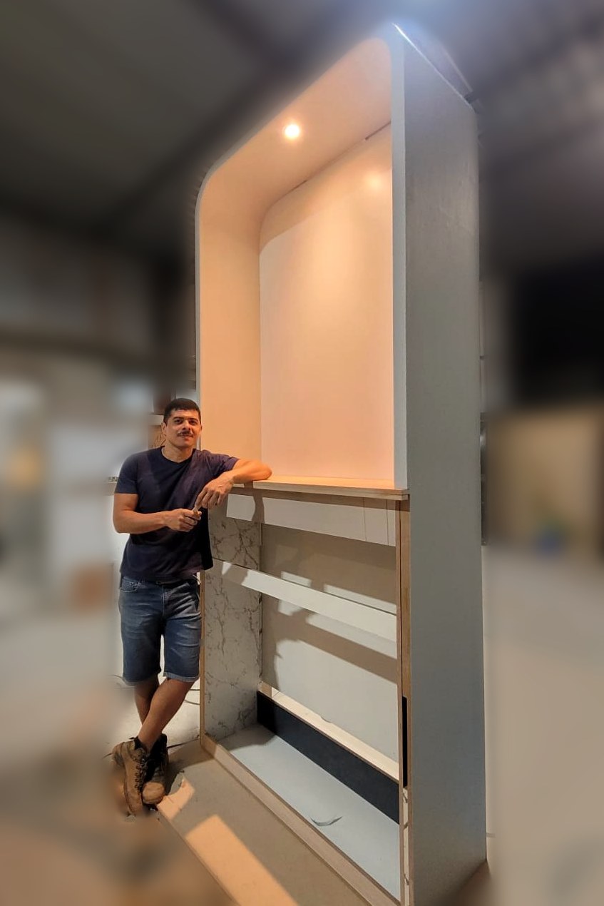 Glaubert Botelho na oficina, ao lado de um oratório em fase de montagem